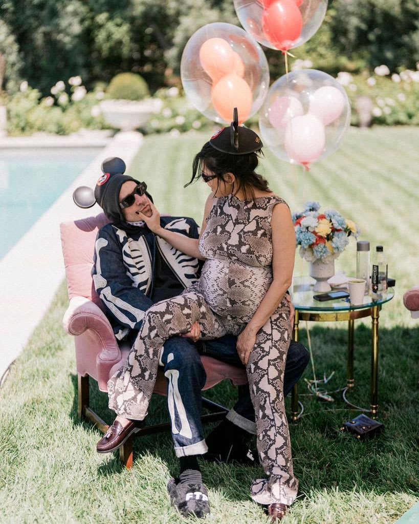 Kourtney Kardashian sitting on Travis Barker's lap at baby shower