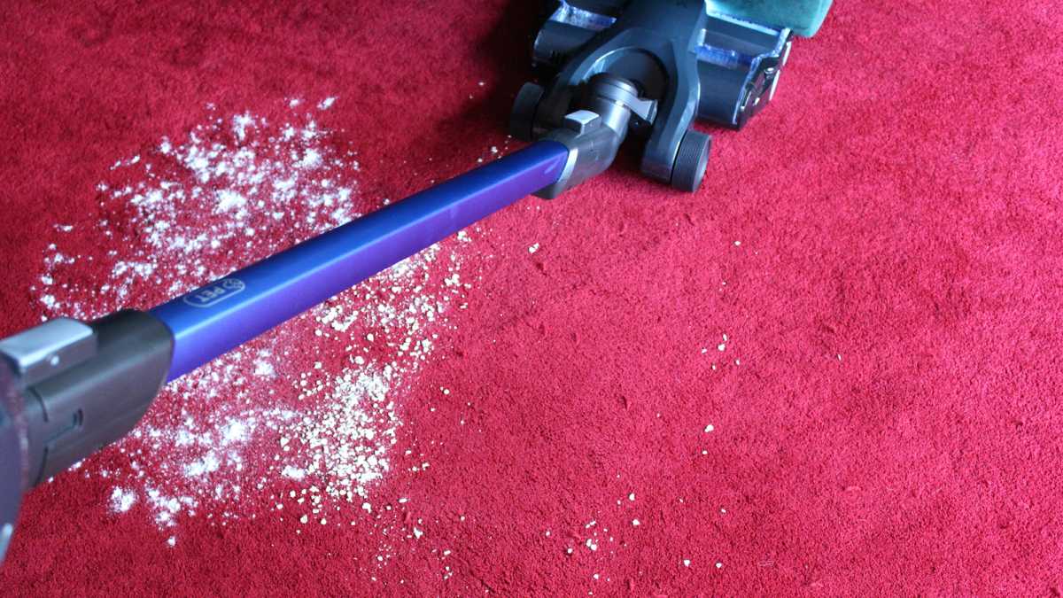 The Vax Blade 5 vacuuming up flour on a red carpet