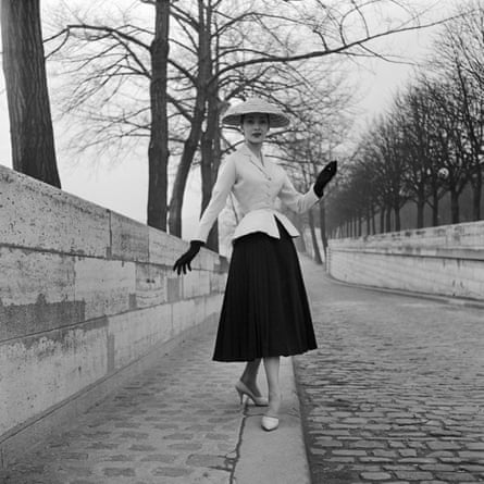 Black and white photo of woman wearing Dior’s New Look, white jacket with nipped-in waist and black skirt and gloves, 1947