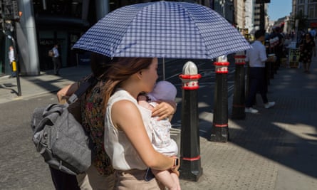 woman carrying a baby under an umbrella during a heatwave